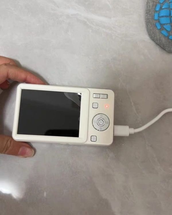 a hand putting the battery into the base of a silver slide camera