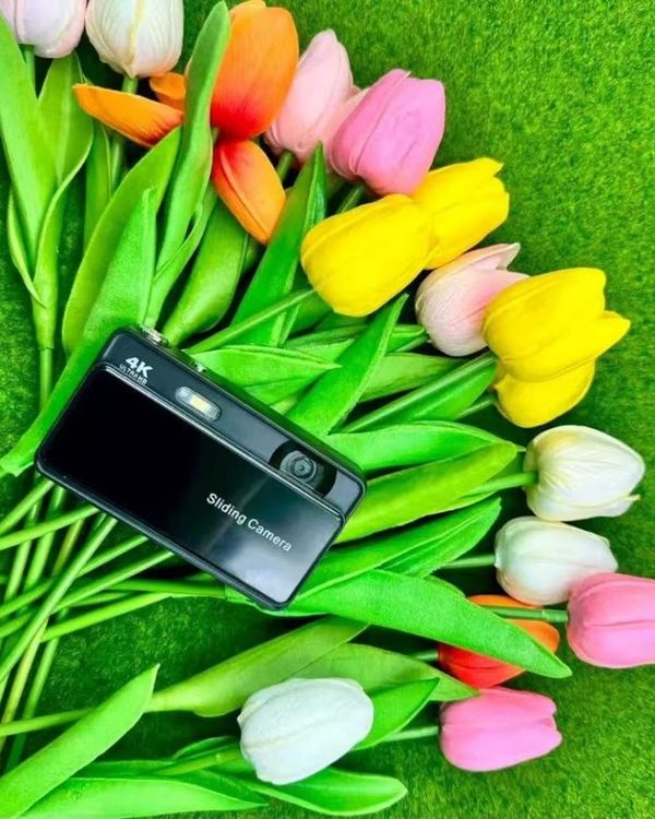 a black slide camera held next to bright tulips
