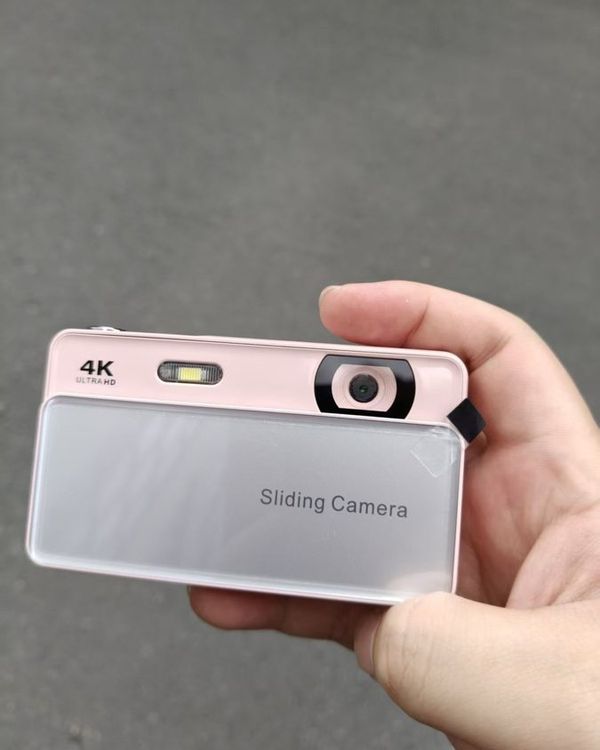 a hand holding a pink and silver slide camera