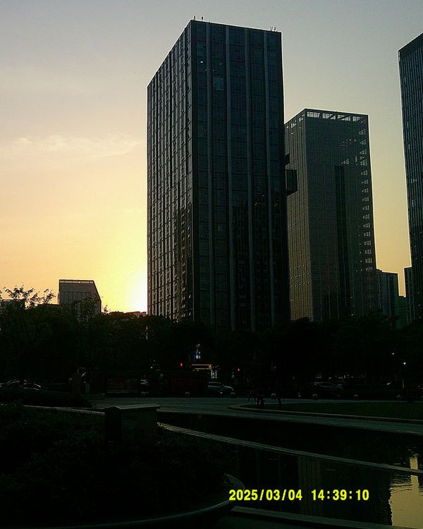 a sunset photo of tall buildings with a date stamp, taken on the camera