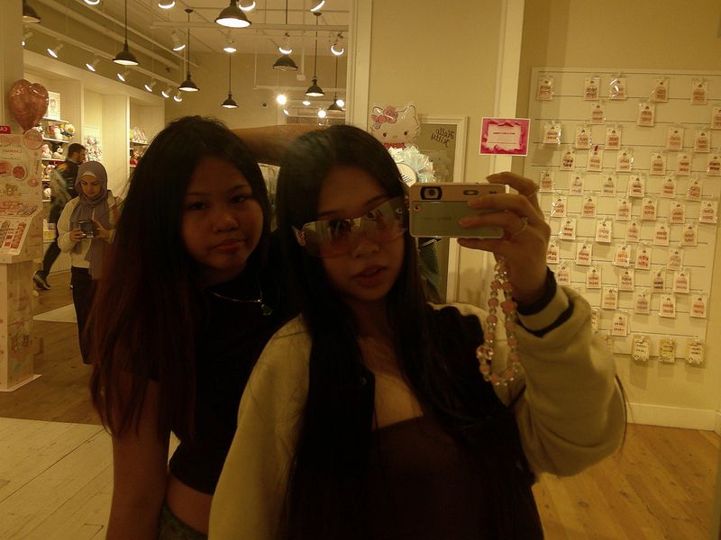two friends taking a mirror selfie in a shop